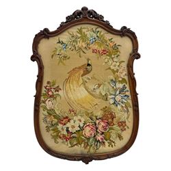 Early 20th century walnut carved needlepoint wall panel, depicting peacock amongst a floral arrangement, framed by carved border with scrolled crest and acanthus leaf accents