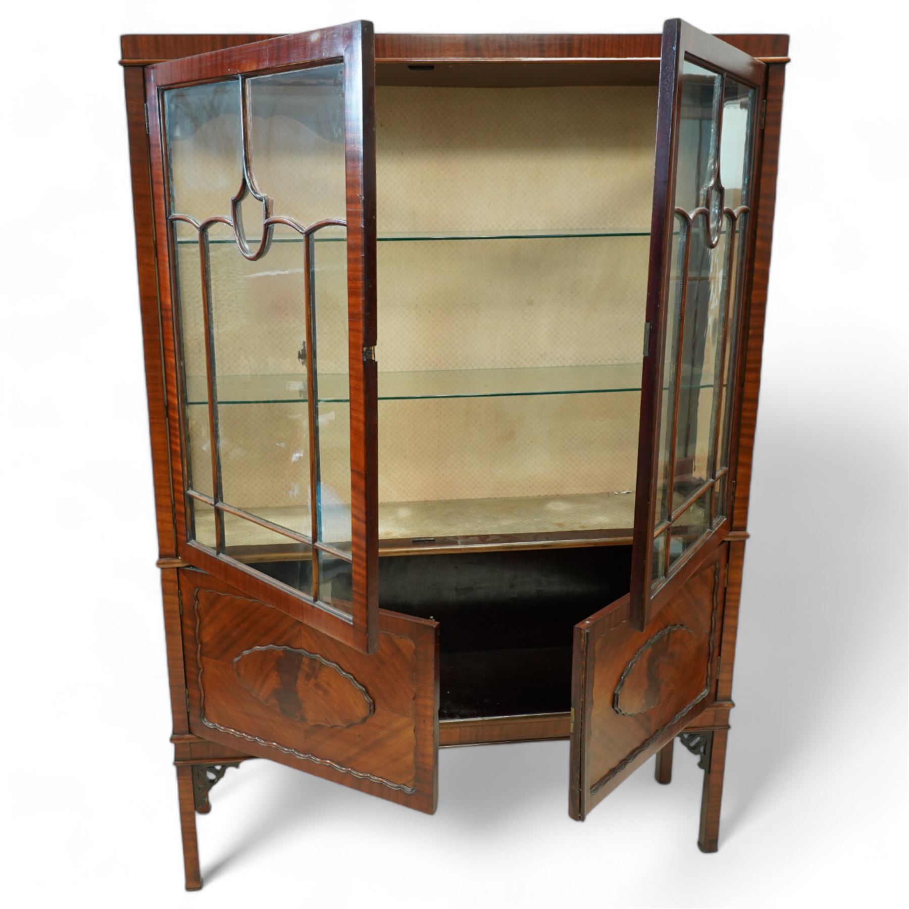 Early 20th century mahogany display cabinet, enclosed by astragal glazed doors over two scalloped panelled cupboard doors, on square supports with pierced scrolling brackets