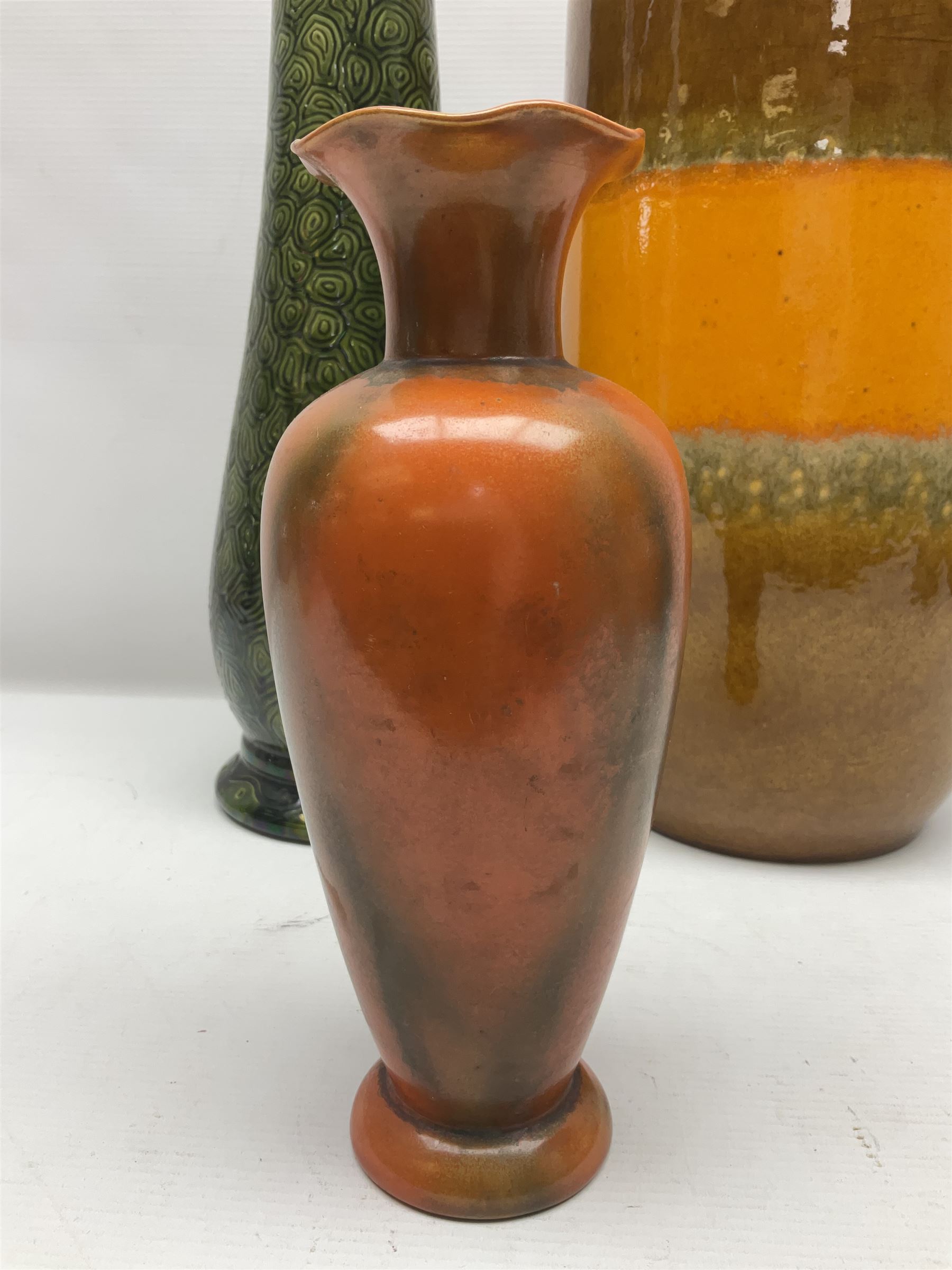 Burmantofts Faience vase, with elongated neck, and concentric circle decoration, in a green lustre glaze, together with a Bretby figure, modelled as a cat with a ball of wool, a Bretby vase, with fluted rim, in orange/red glaze, frog jug and a large West German vase, tallest H38cm