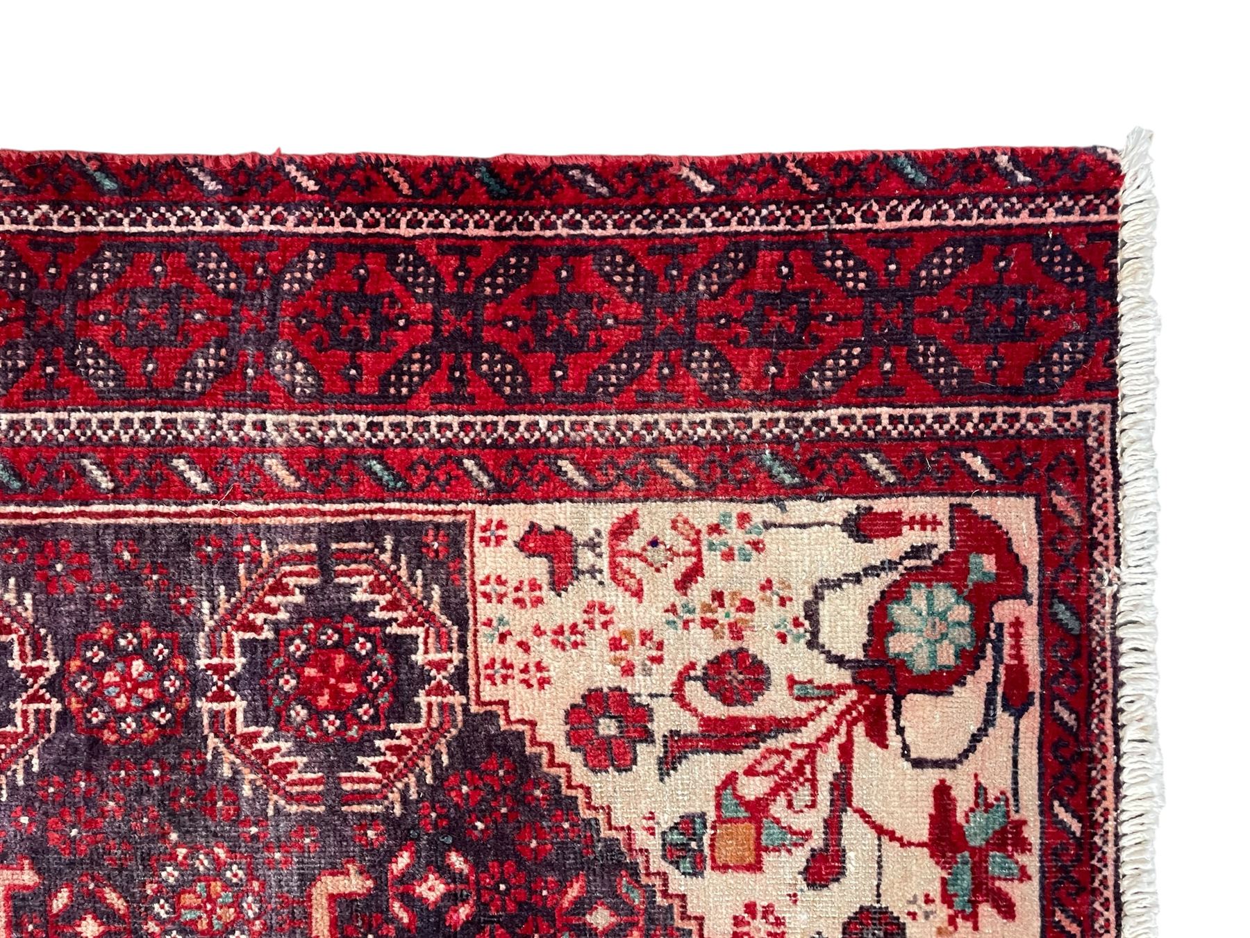 Persian Baluchi dark indigo and crimson ground rug, the field decorated with rows of repeating Pitrak motifs and surrounded by small bird and flower head motifs, floral urn decorated spandrels, repeating Pitrak border within guard stripes