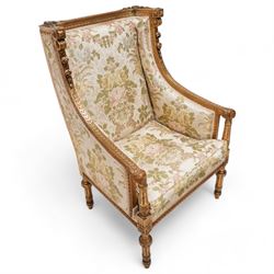 Late 19th century French gilt wood and gesso enclosed armchair, the cresting carved with floral bouquets over foliate moulding, upholstered in floral pattern fabric with repeating pattern, down-swept arms with scrolled acanthus leaf terminals, on turned and fluted feet carved with foliage 