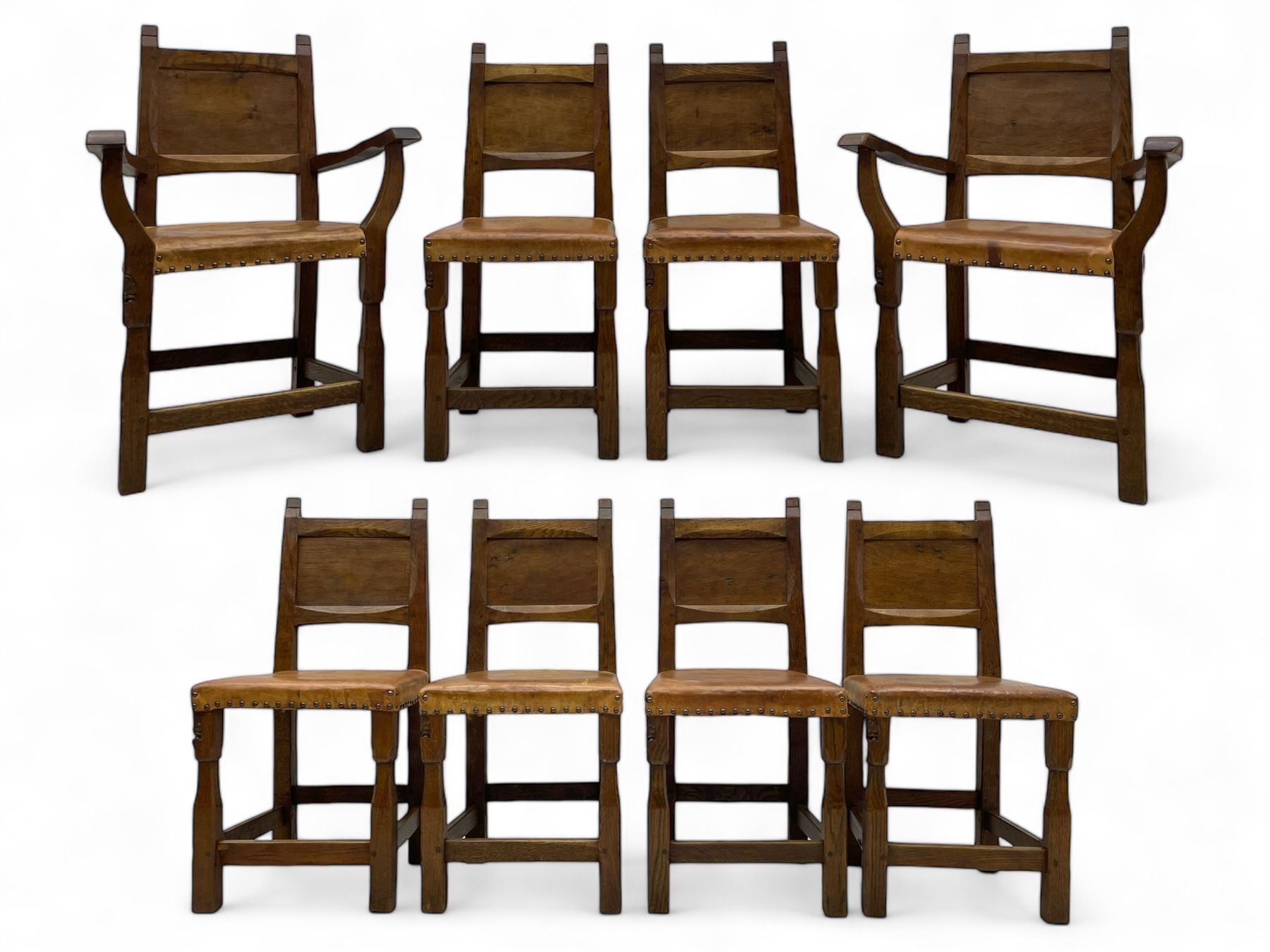 Gnomeman - set of eight (6+2) oak dining chairs, adzed panelled back over tan leather upholstered seat with applied stud band, on square supports united by plain stretchers, each chair carved with gnome signature, by Thomas Whittaker, Littlebeck, Whitby