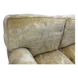 Contemporary two-seat sofa, upholstered in damask fabric with a pale gold floral pattern, rolled arms, loose back and seat cushions, on matching skirted base with concealed castors