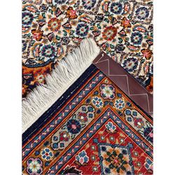 Persian Bidjar ivory and indigo ground rug, large central rosette medallion surrounded by floral herati motifs, crimson ground border decorated with repeating palmettes, within guard stripes decorated with small flower head motifs 