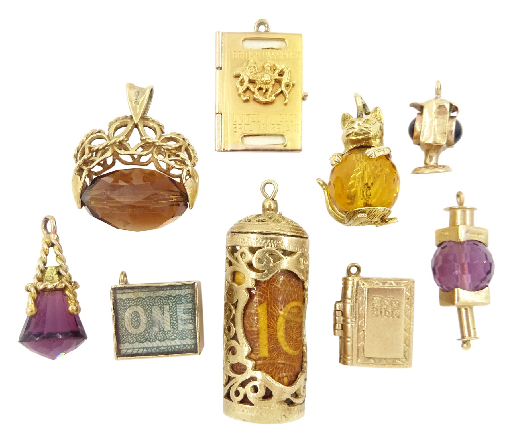 Nine gold pendant / charms including money roll, stone set cat, swivel fob, lanterns, passport etc, all 9ct