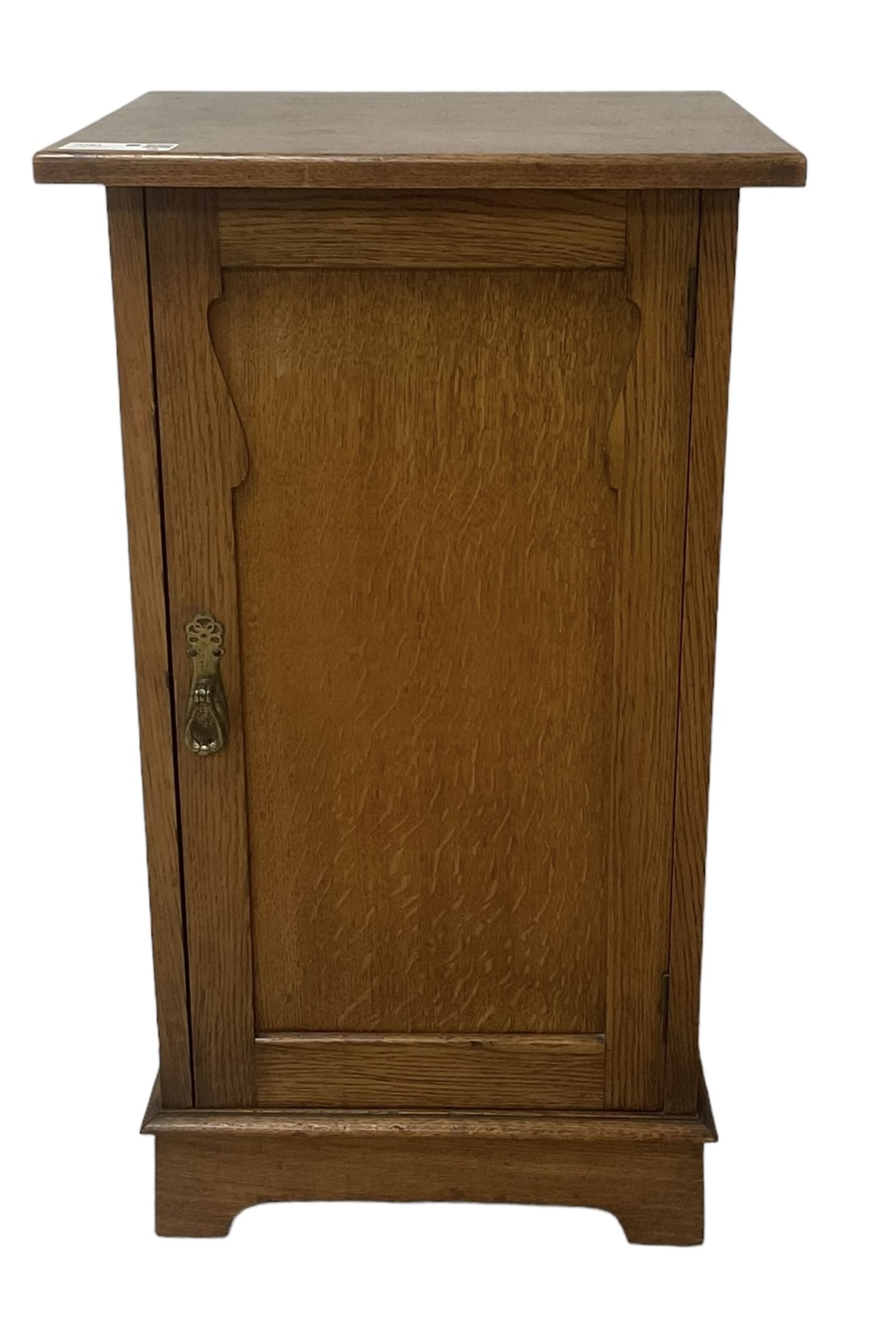 Arts and Crafts period oak pot cupboard, shaped panelled door enclosing single shelf