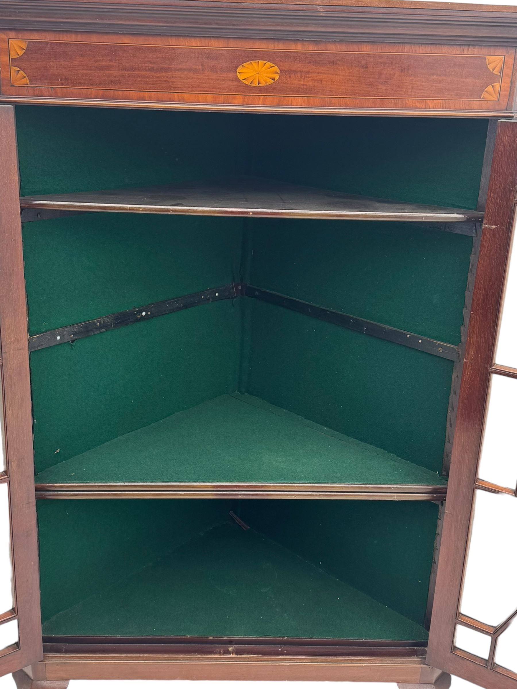 Edwardian mahogany corner cabinet, projecting cornice over inlaid frieze, two astragal glazed doors enclosing shelved interior, on cabriole supports