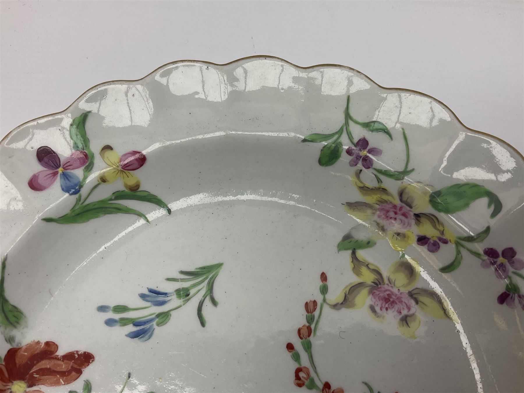 Three 18th century Worcester desert dishes, the first example decorated in the Scarlet Japan pattern, circa 1790, painted with alternating panels of Kakiemon style prunus blossom and chrysanthemum, and orange ground panels with gilt fret detail, D19cm, the second example, circa 1770, decorated with Kakiemon style chrysanthemums and foliage within shaped reserves upon a blue scale ground, with fretted square pseudo mark beneath, D19cm, and the third, circa 1770, painted with polychrome floral sprays and sprigs, D20cm