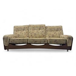 Mid-20th century three-seat sofa with floral patterned upholstery, supported by a sculpted teakwood frame with curved cutout detailing, loose cushioned back and seat, on tubular metal feet