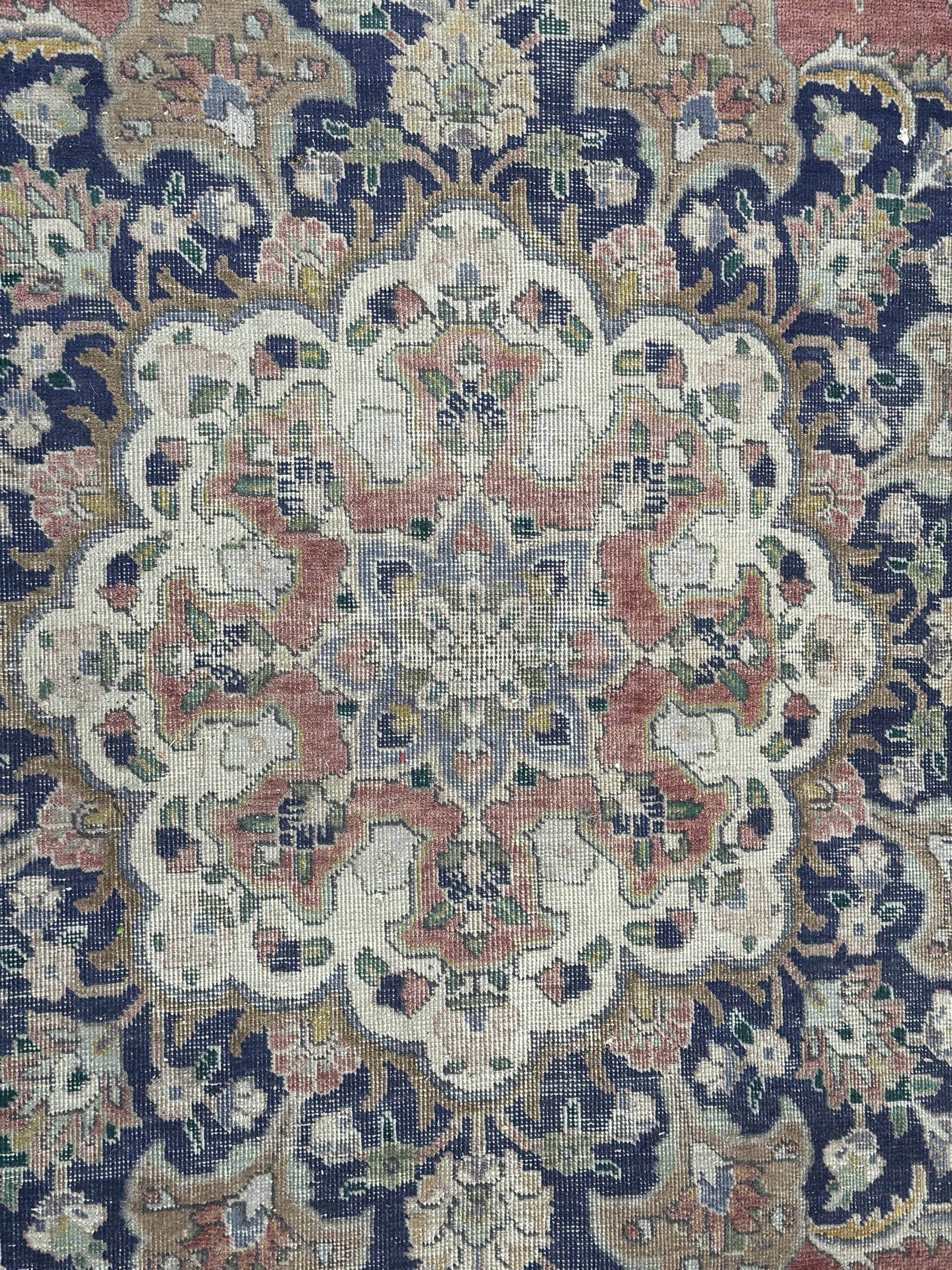 Persian rose ground rug, large central floral medallion surrounded by scrolling foliate and floral motifs, pale green spandrels, wide border in pale green and navy with intricate floral designs, framed by multiple guard stripes with repeating floral and geometric patterns