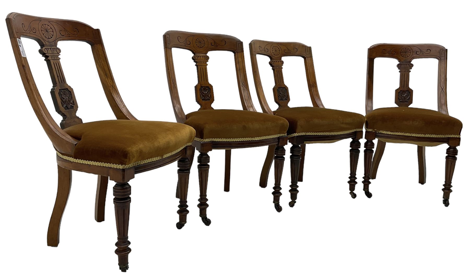 Set of four late Victorian walnut dining chairs, carved with stylised floral decoration and scrolling branches, upholstered seat, on turned and fluted supports 