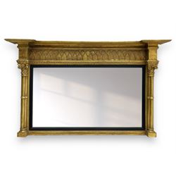 Regency design giltwood overmantel mirror, projecting cornice over pointed arcade frieze and foliate moulded upper edge, plain mirror plate within reed moulded ebonised slip, flanked by cluster columns with acanthus and scroll decorated Composite order capitals 