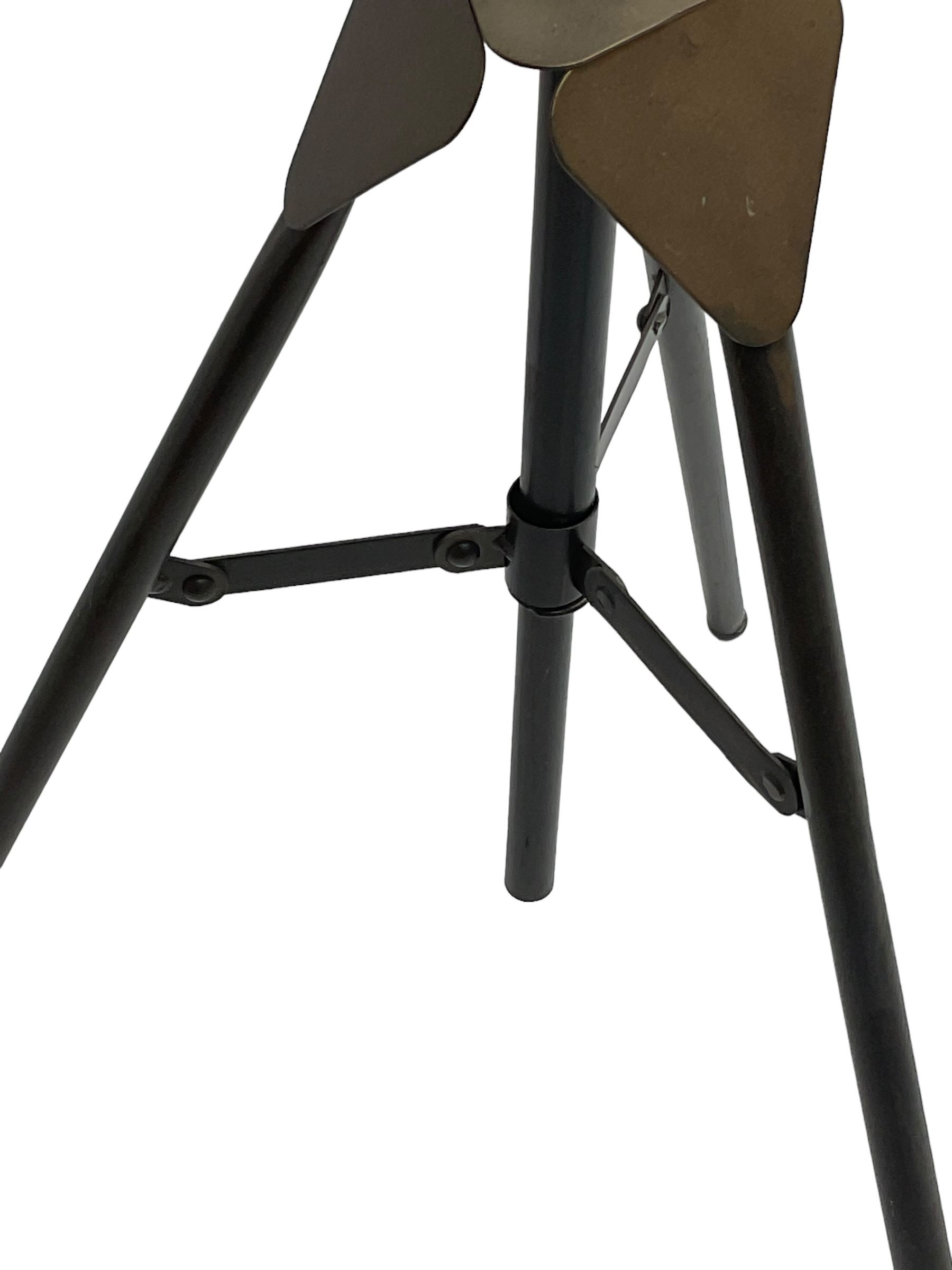 Industrial tripod spotlight, with a metal shade and wire guard, supported by a height-adjustable tripod base, the head equipped with an adjustable tilt mechanism