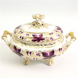 Pair of early 19th century porcelain sauce tureens and covers on stands, possibly Coalport, painted with bands of purple and gilt fruiting vines, within gadroon borders, the stands with naturalistic oak leaf and entwined moulded  handles, the covers with flower knop handles, stand L24cm, overall H18cm