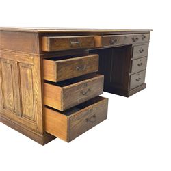 Large 20th century oak twin pedestal desk, moulded rectangular top over nine drawers, panelled pedestals, on moulded plinth base 