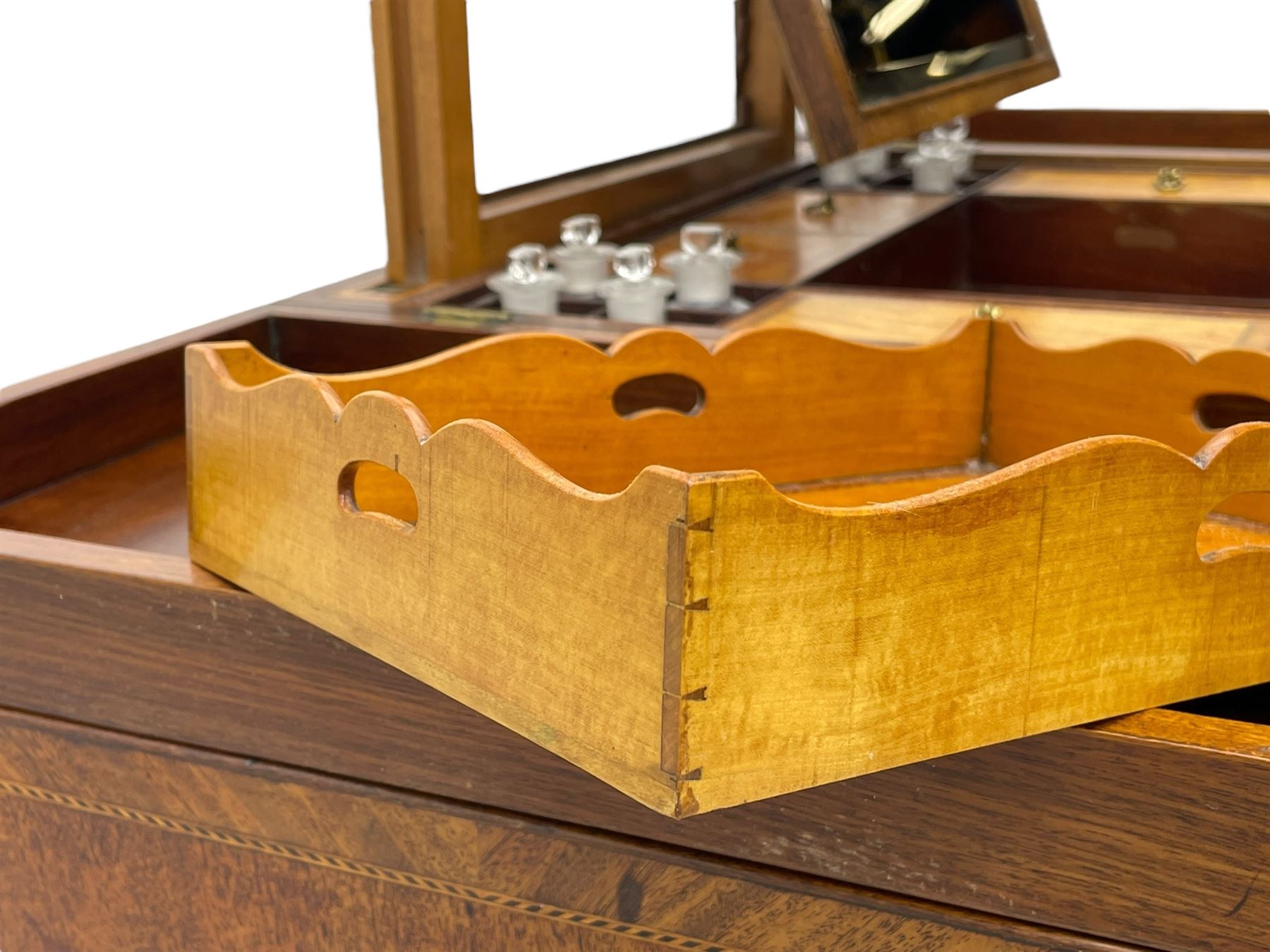 Late 19th century mahogany and satinwood dressing chest, the raised middle section hinges to reveal an interior fitted with lidded compartments, removable tray, single drawer and glass scent bottles, lift-up bevelled mirror with adjustable hinged mechanism, fitted with a further eight cock-beaded graduating drawers and curved kneehole with double cupboard, square tapering supports on brass cups and castors, inlaid throughout with checkered stringing, ornate Rococo cast gilt metal handles