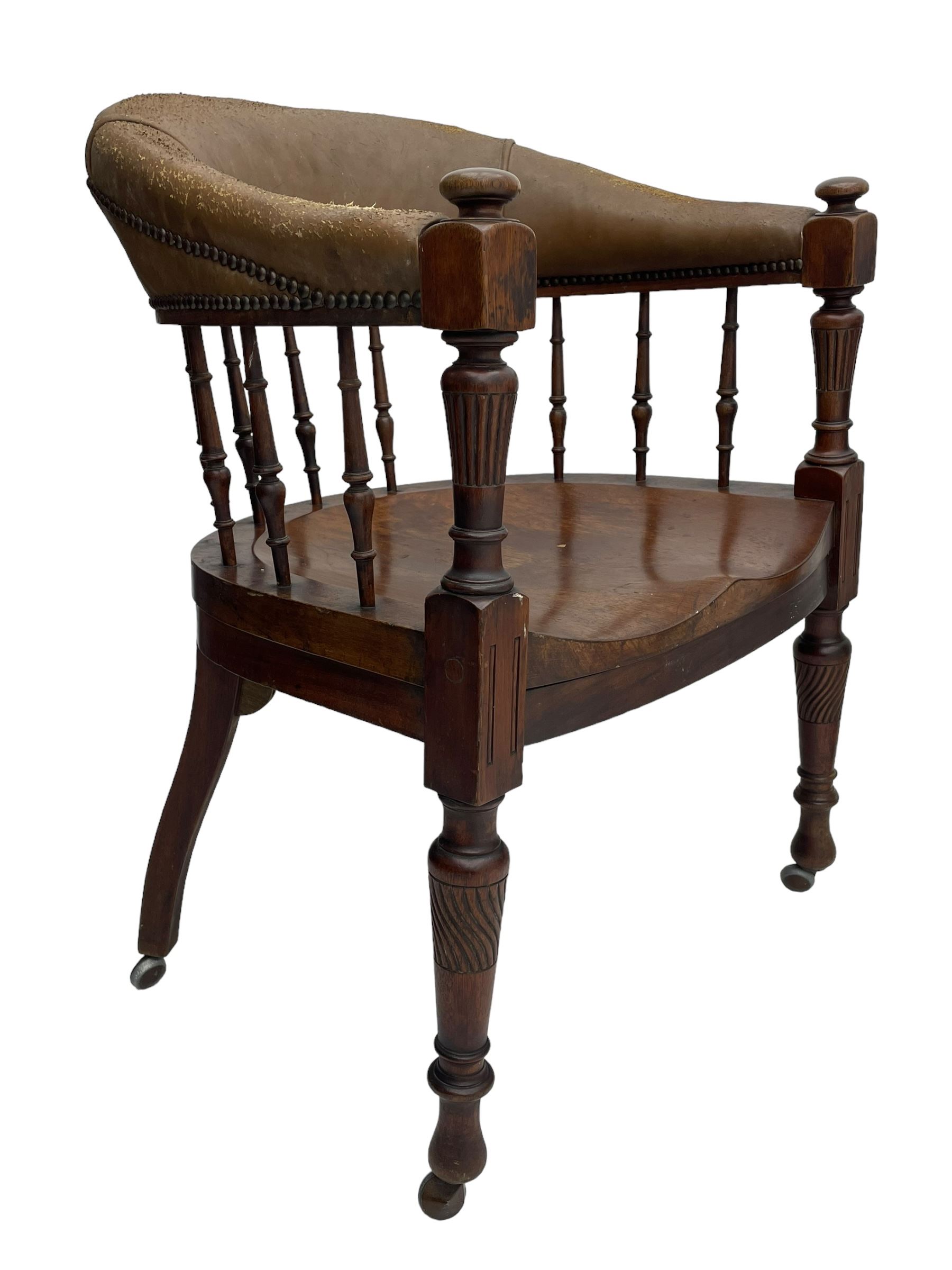 Pair of late Victorian walnut tub-shaped elbow chairs, the cushioned cresting rail upholstered in leather on spindle turned supports, dished saddle seat on turned supports