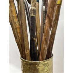 Oak barley twist stick stand, with a collection of walking sticks including examples with carved pommels, horn handles, silver collar etc, together with brass stick stand 