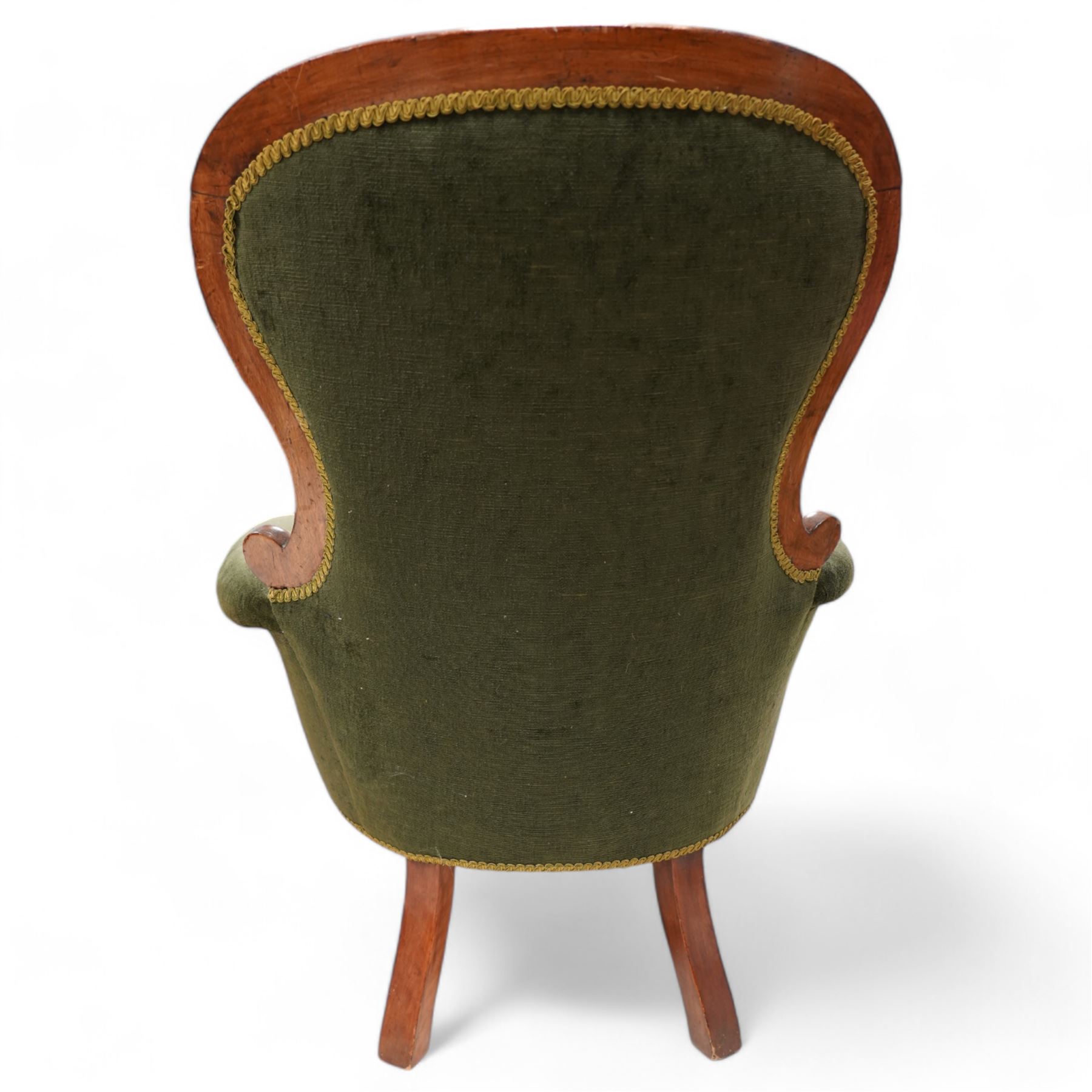 Victorian mahogany spoonback armchair, moulded frame with scroll carved terminals, upholstered in buttoned green fabric, rolled arms with foliage scroll carved facias, on turned front feet with brass cups and castors 