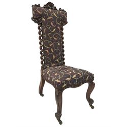 Victorian walnut prie-dieu chair, cresting rail carved with cartouche and extending scrolling foliage, back flanked by spiral turned column uprights, upholstered in foliate patterned fabric, raised on cabriole supports with scroll feet and castors