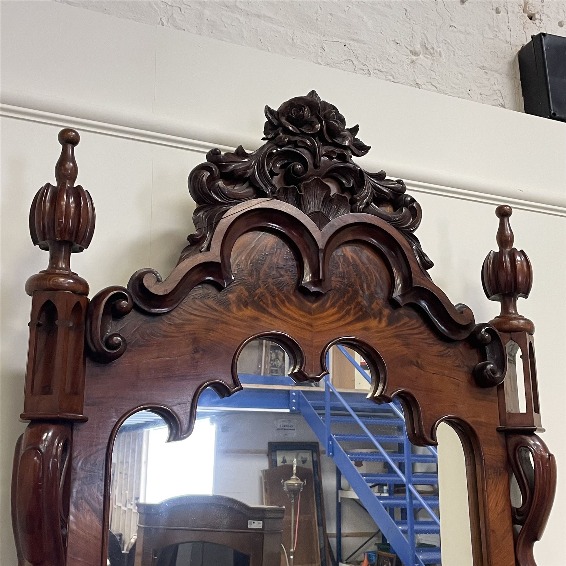 Tall Victorian figured mahogany twin pedestal dressing table, the tall mirror with flower head and scrolled leaf carved pediment, flanked by two turned and carved finials over faceted lancet arched lantern tops, plane mirror plate enclosed by shaped frame, pierced and undulating moulded uprights, on C-scroll and curled leaf carved supports fitted with cast brass hinged candle sconces, each pedestal fitted with two small trinket drawers over larger drawer and panelled cupboard, canted corners with matched upright mounts, the cupboard doors enclosing slides, on scroll carved feet 