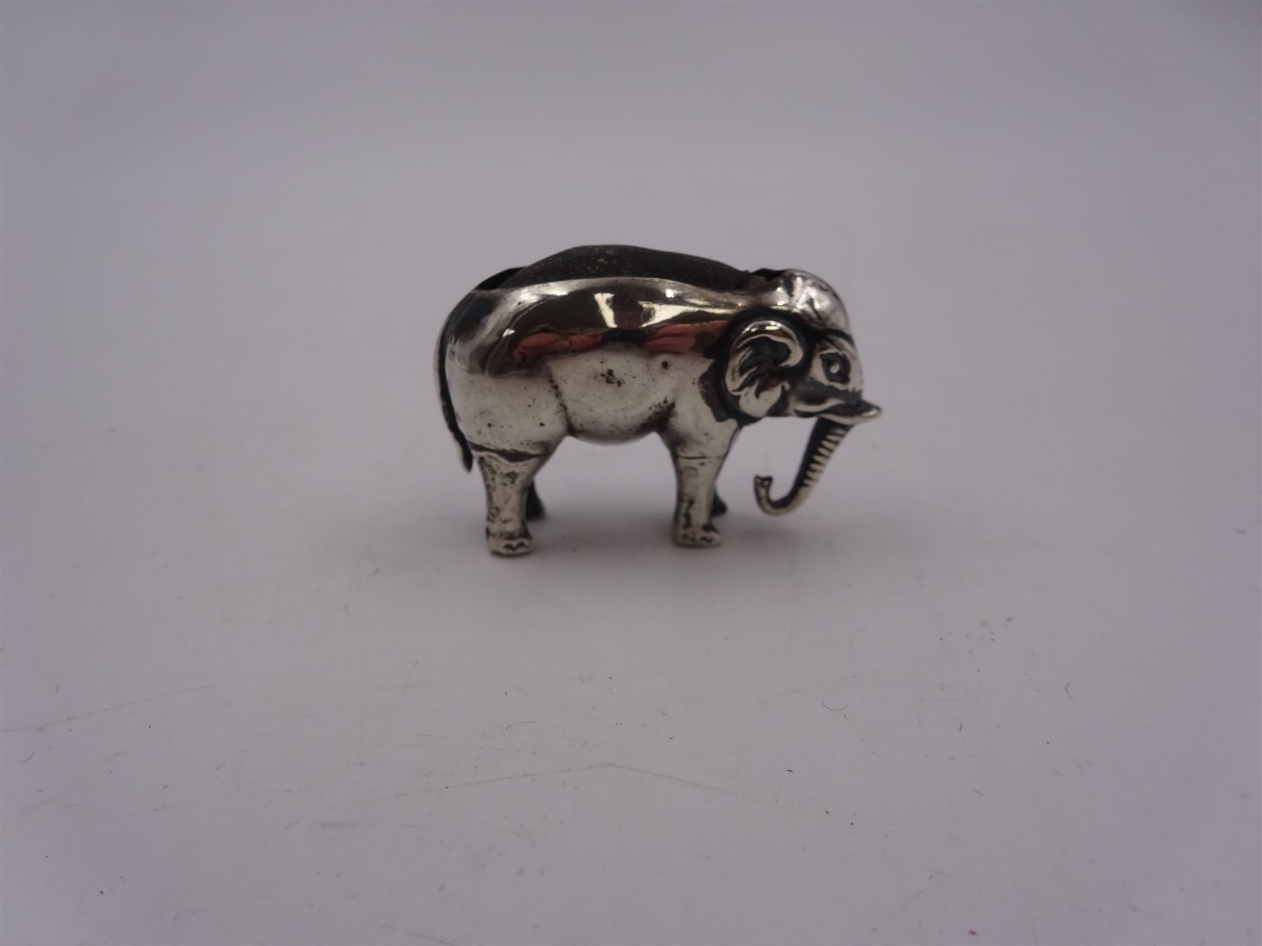 Edwardian silver mounted novelty pin cushion, in the form of an elephant, with cushioned back, hallmarked Birmingham 1906, maker's mark worn and indistinct, L4cm, H3.5cm