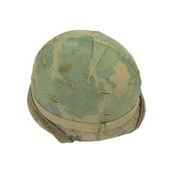 Collection of nine military helmets, including several with camouflage covering 