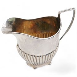 George III silver sauce boat with leaf capped scroll handle and shaped supports, Newcastle assay Maker John Langlands I and John Robertson I and a silver cream jug Birmingham 1907 