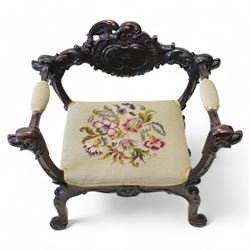 19th century Italian heavily carved stained walnut open armchair, the back rail carved with a large central cartouche decorated with extending acanthus and C-scroll motifs, the wing and arm terminals carved in the form of snarling dog masks, seat upholstered in floral needlework, shaped apron carved with cartouche and shell motifs, over out-splayed cabriole supports with acanthus moulding, terminating to paw feet