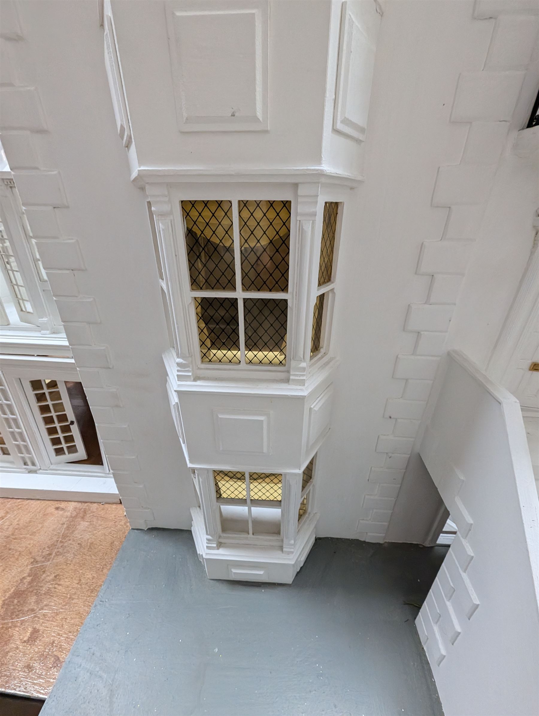 Large three storey modern dolls house, painted white with latticed windows, grey roof and metal fencing, with decorated interior, together with two dolls house garden rooms and two conservatories