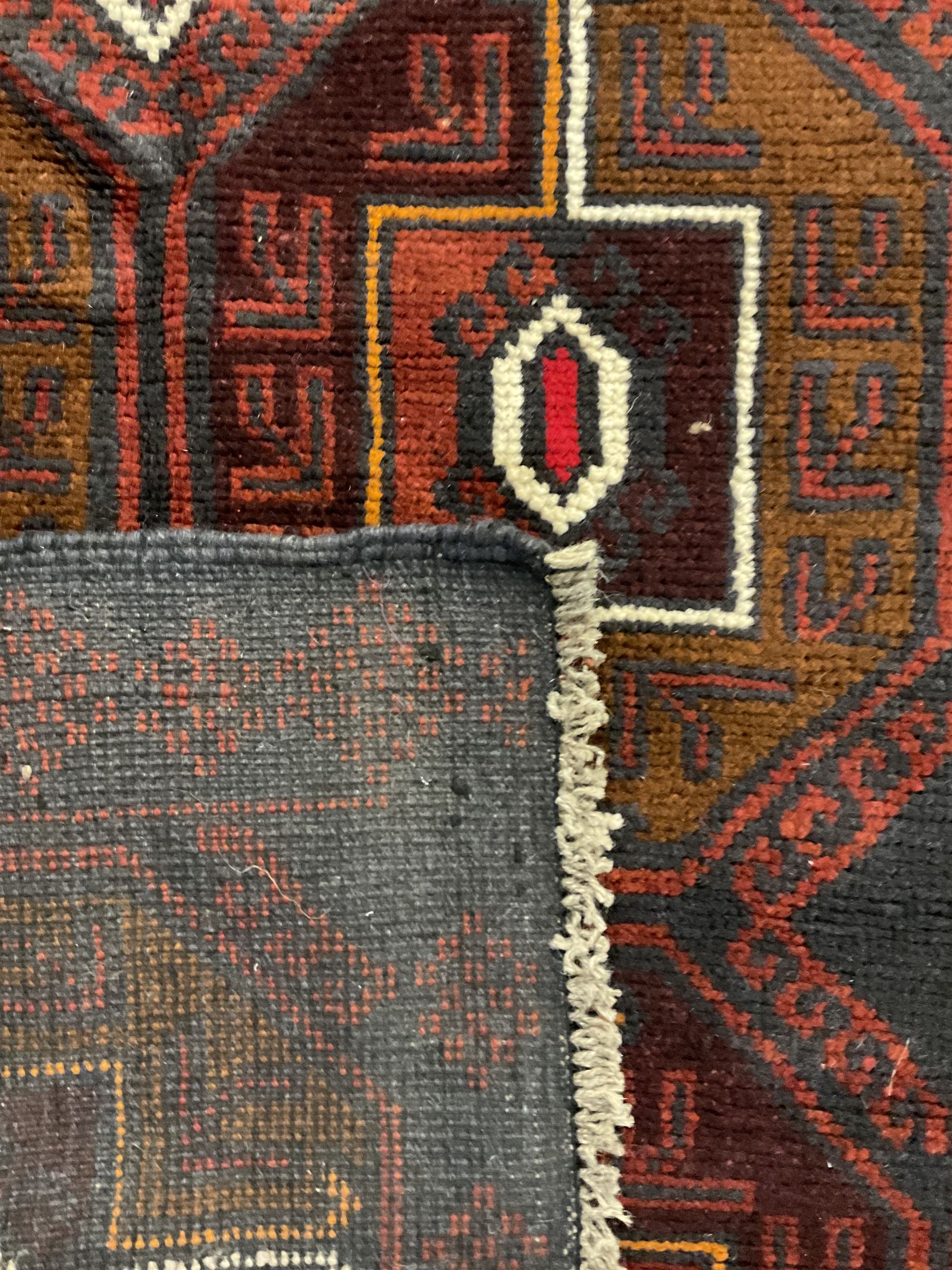 Baluchi red and blue ground rug, the field decorated with large six Gul motifs