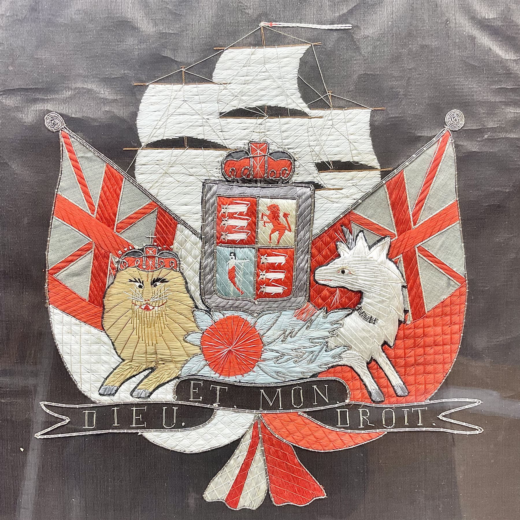 Early 20th century silk needlework panel, depicting a ship in full sail and Royal Coat of Arms to centre, with red and white ensigns to either side, lion and unicorn below with quote 'Dieu Et Mon Droit', upon a black silk ground within gilt frame, H59cm