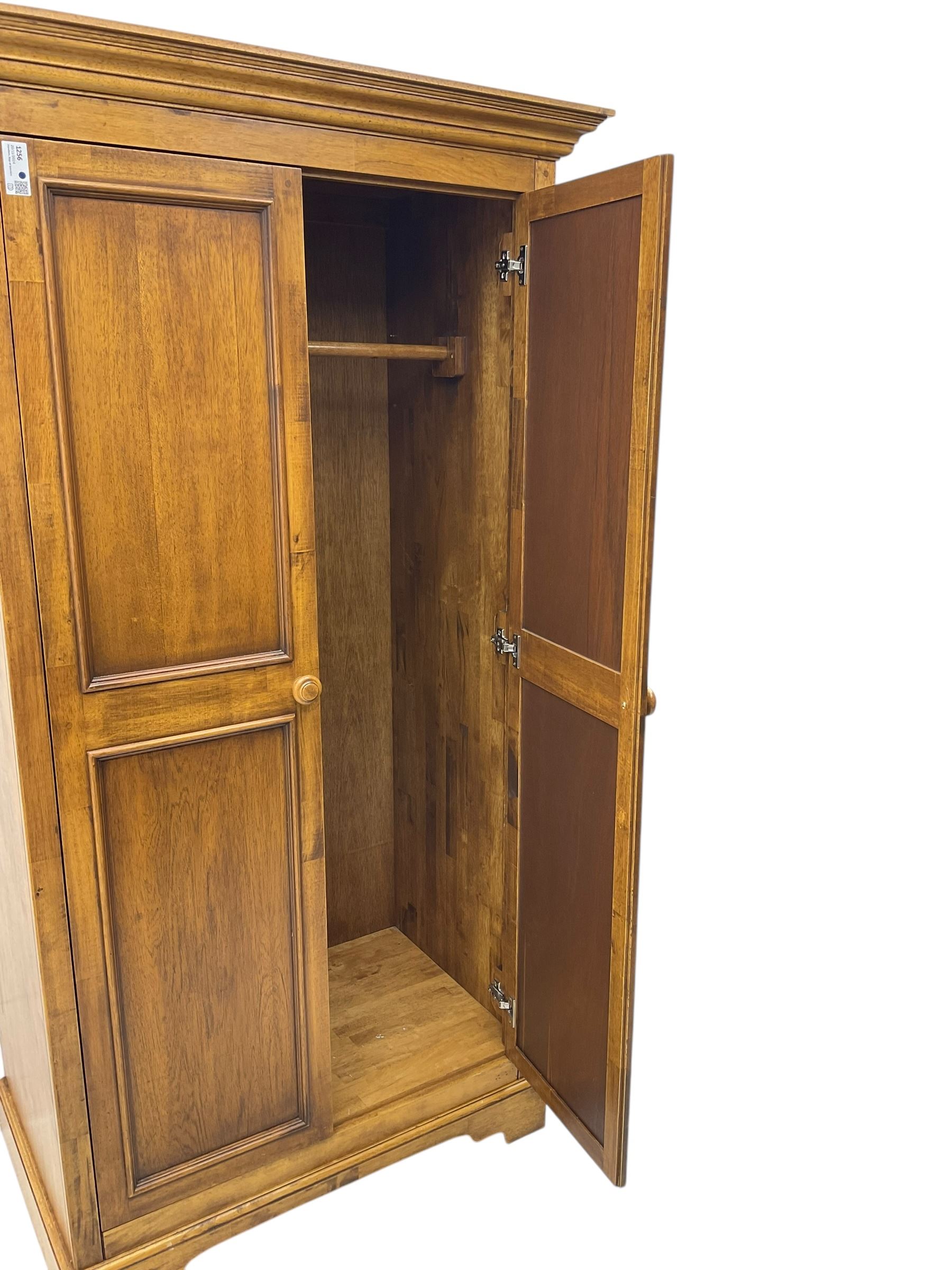 Hardwood double wardrobe, enclosed by two panelled doors, on bracket feet 