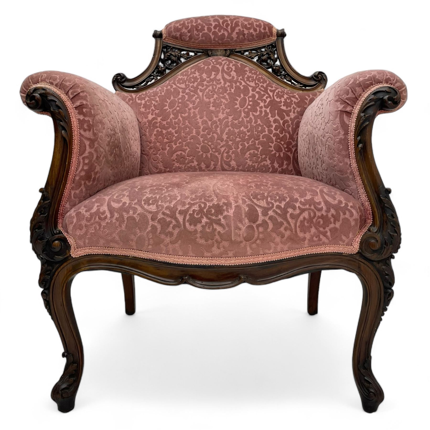 Late 19th century carved walnut framed armchair, the upper spandrels pierced and carved with curled acanthus leaves, upholstered in pink foliate pattern fabric, acanthus leaf carved and scrolled arm facias terminating to cabriole supports, leaf carved terminals 