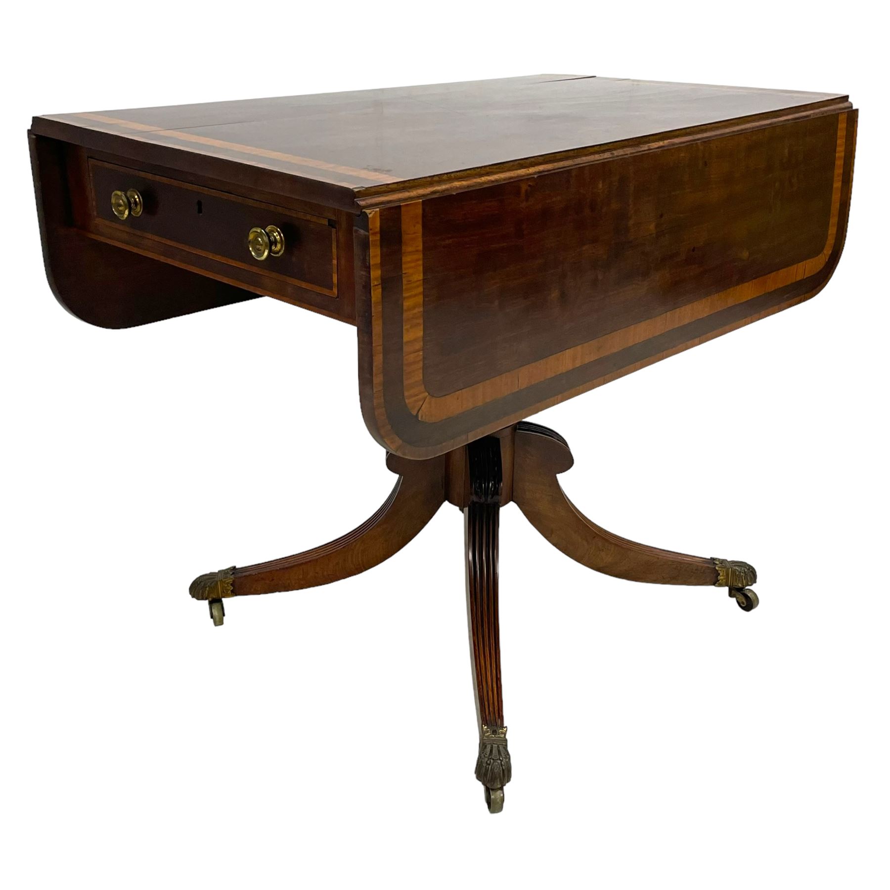 Early 19th century mahogany Pembroke table, rectangular drop-leaf top with rounded corners inlaid satinwood bands, single end drawer and opposing false drawer, turned pedestal on four acanthus carved and reed moulded splayed supports, cast brass cups and castors 