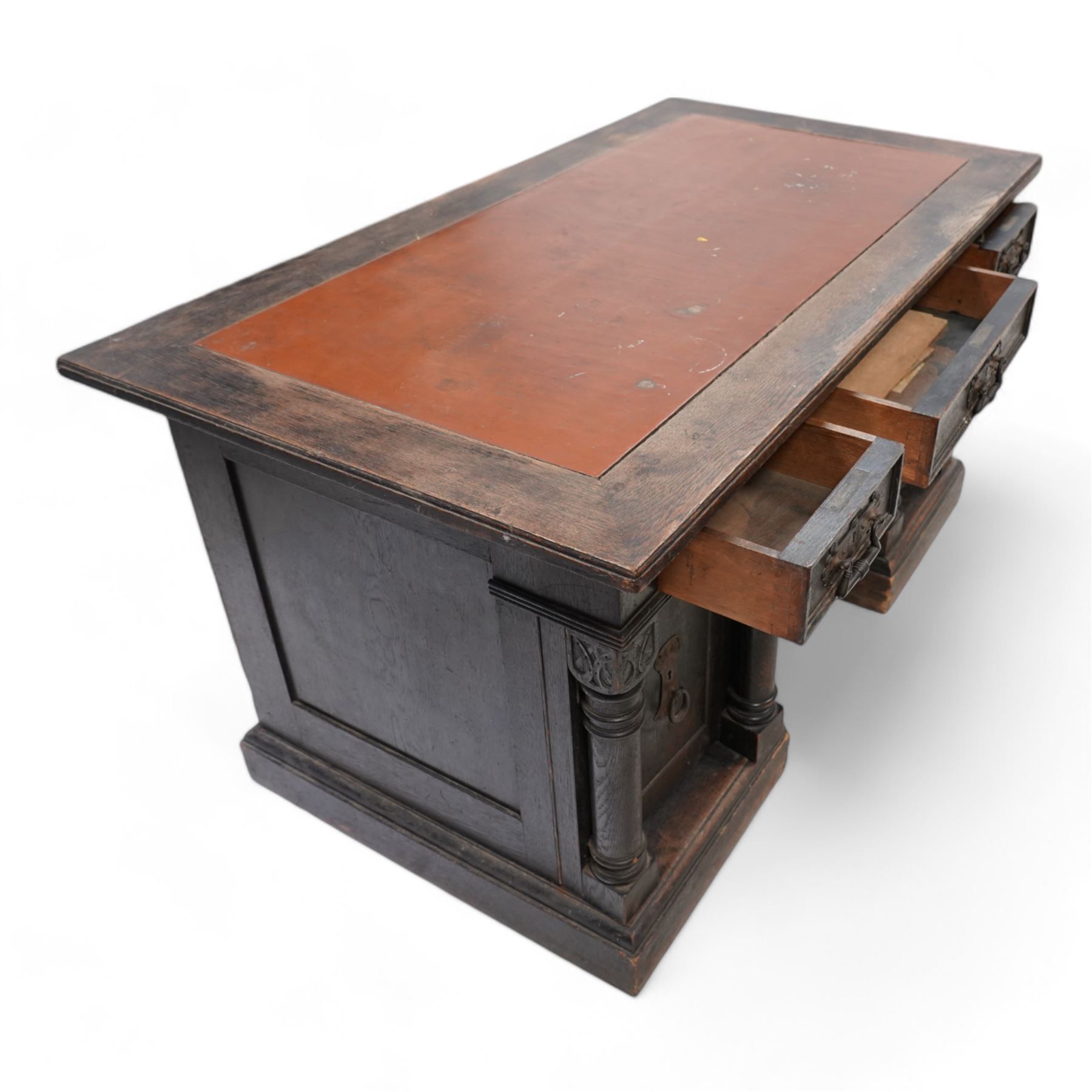 Late Victorian oak twin pedestal desk, rectangular moulded top with brown leather inset, three drawers fitted with Aesthetic Movement angular handles, each pedestal enclosed by door with turned columns, on moulded plinth base 