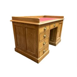 Early 20th century oak ‘Headmasters’ twin pedestal desk, three-quarter raised gallery back and inset leather writing surface, fitted with central drawer flanked by four graduating drawers and single cupboard