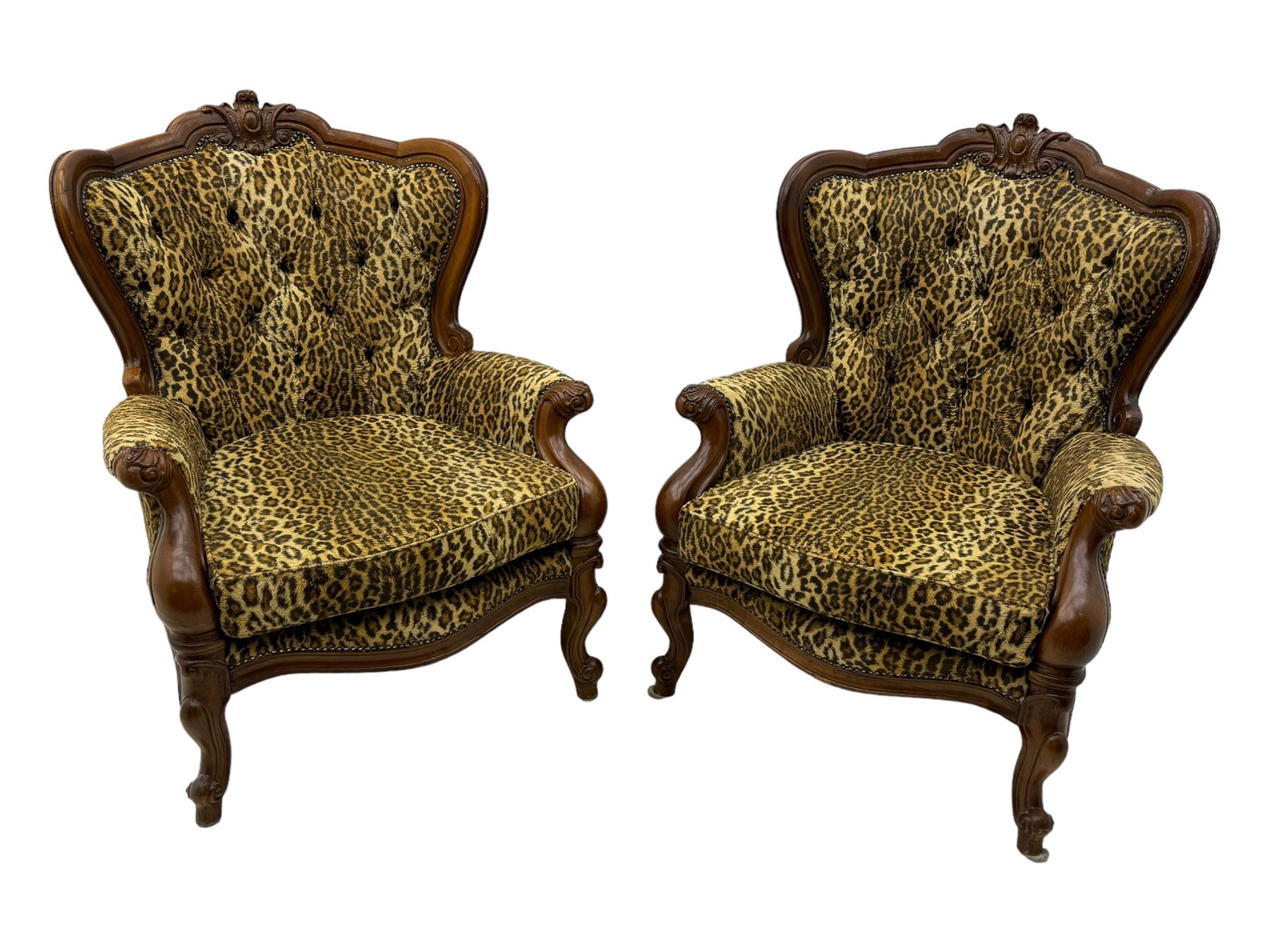 Pair of Victorian design stained beech armchairs, upholstered in leopard print fabric, with carved top rail over button-tufted backrest, scroll arms, serpentine front rail, raised on cariole supports