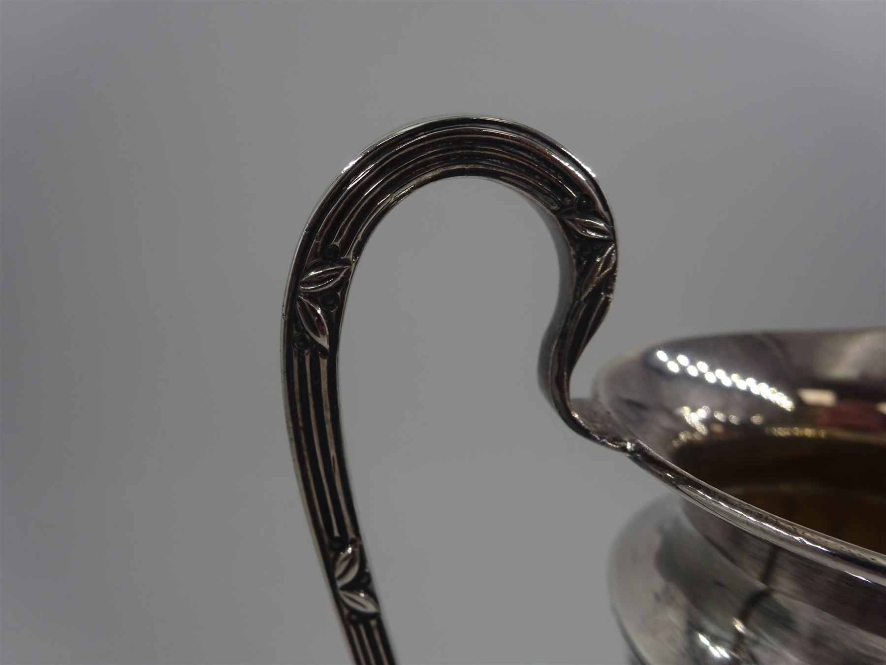 Early 20th century silver cream jug, of helmet form with faceted body and scroll handle, upon stepped circular foot, hallmarked Walker & Hall, date mark indistinct, H16.5cm