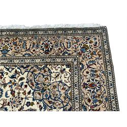 Persian Kashan ivory ground rug, central floral medallion surrounded by interlacing leafy branches and stylised plant motifs, scrolling spandrels, the border decorated with trailing branch and repeating palmettes, within floral pattern guard stripes 