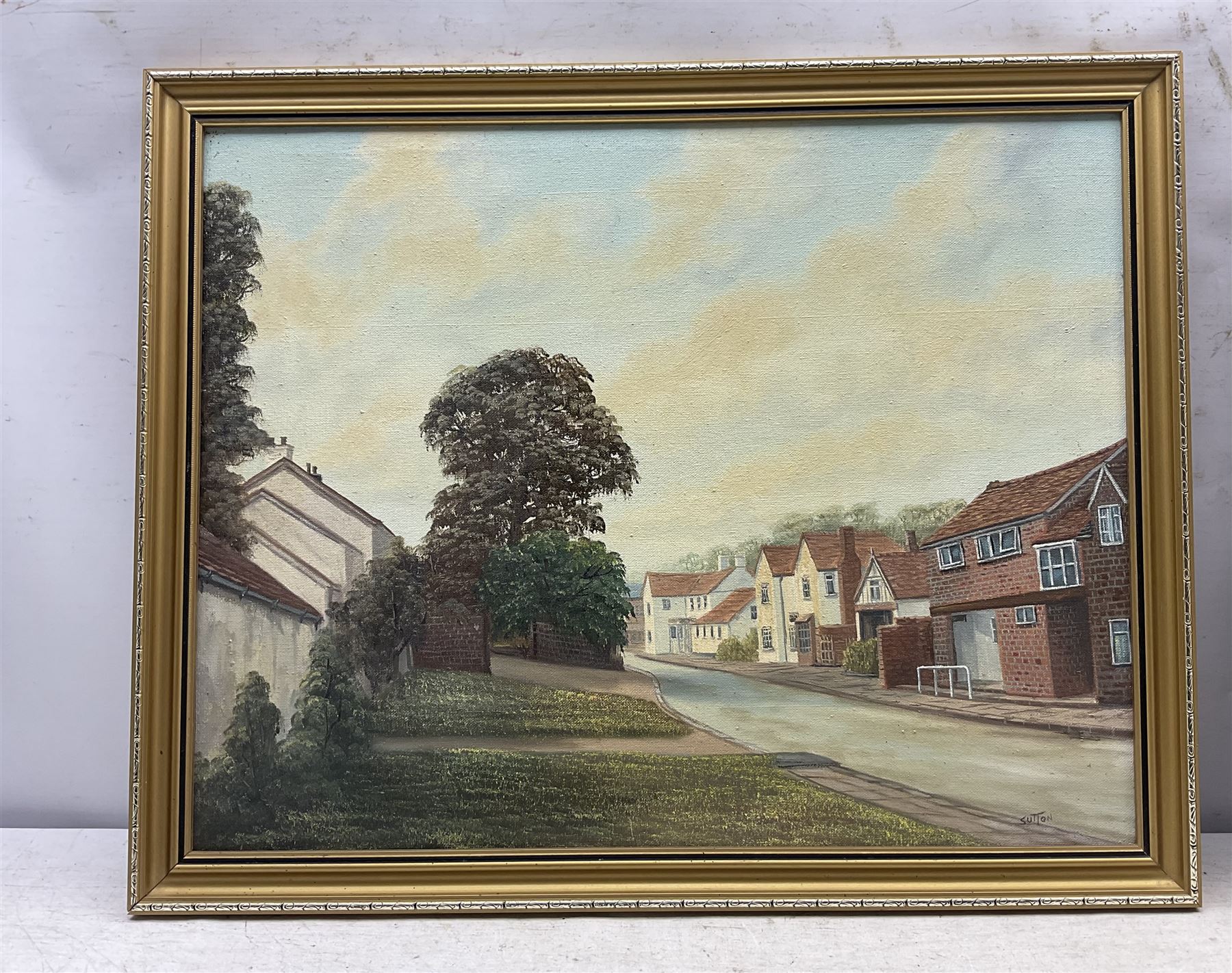 Keith Sutton (British 1924-1991): A Sussex Street, oil on canvas signed 44cm x 56cm; R Gill (Northern British 20th Century): Yorkshire Village on a Hill, oil on board signed 40cm x 70cm (2)