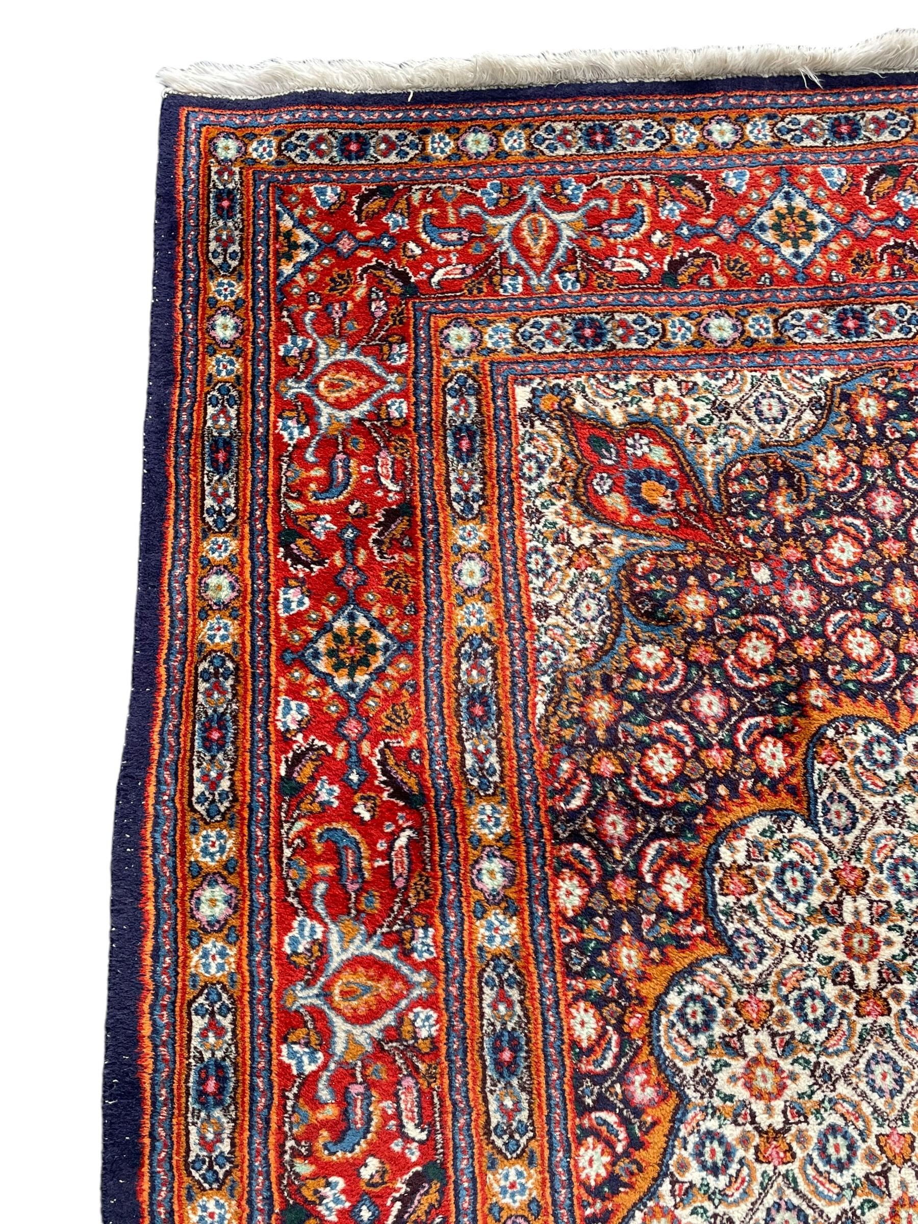 Persian Bidjar ivory and indigo ground rug, large central rosette medallion surrounded by floral herati motifs, crimson ground border decorated with repeating palmettes, within guard stripes decorated with small flower head motifs 