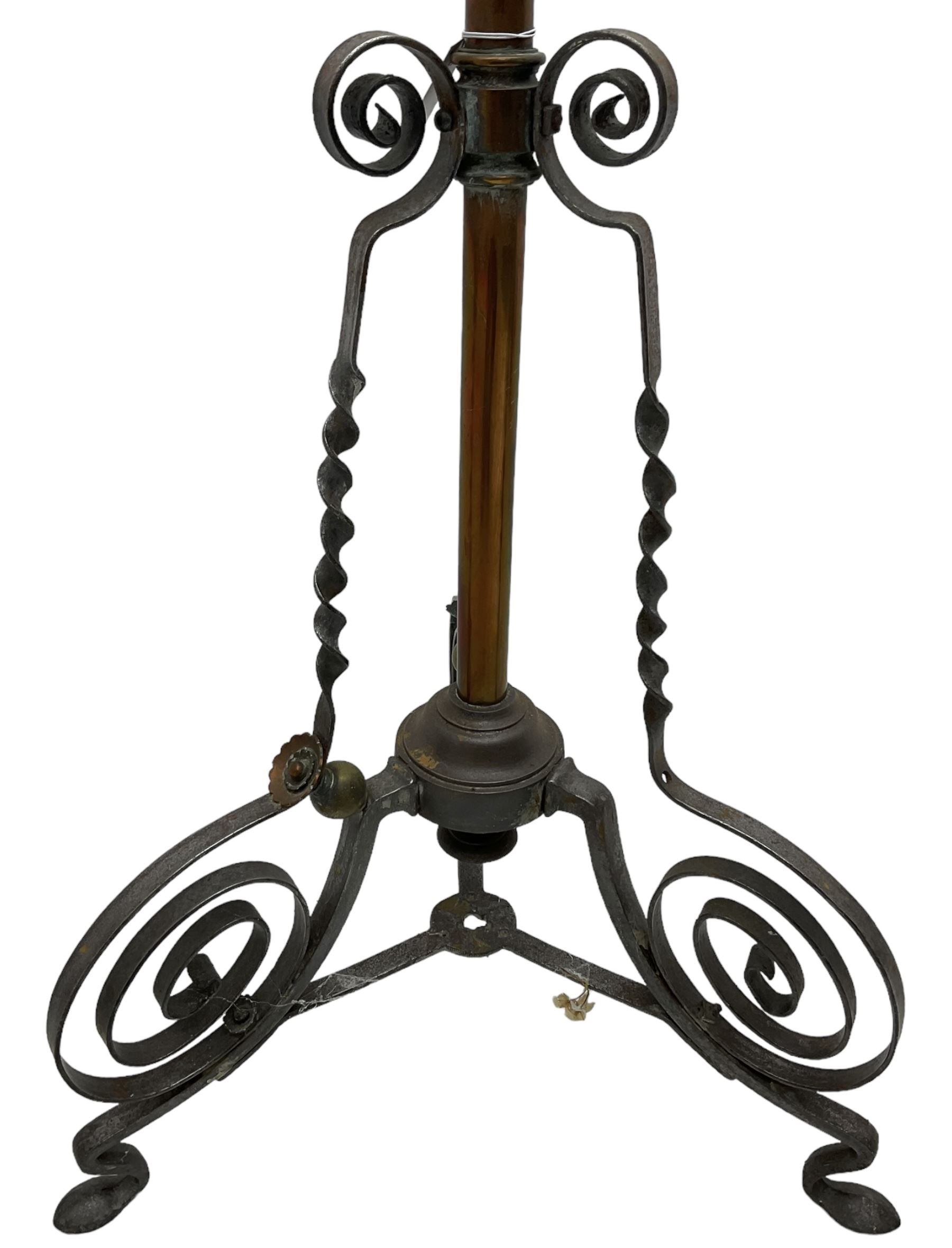 Late 19th to early 20th century wrought metal and copper telescopic oil standard lamp, the lamp and reservoir on scrolled supports with waved band, handle operating telescopic action, tripod base with scrolled terminals and twisted decoration, splayed pad feet 