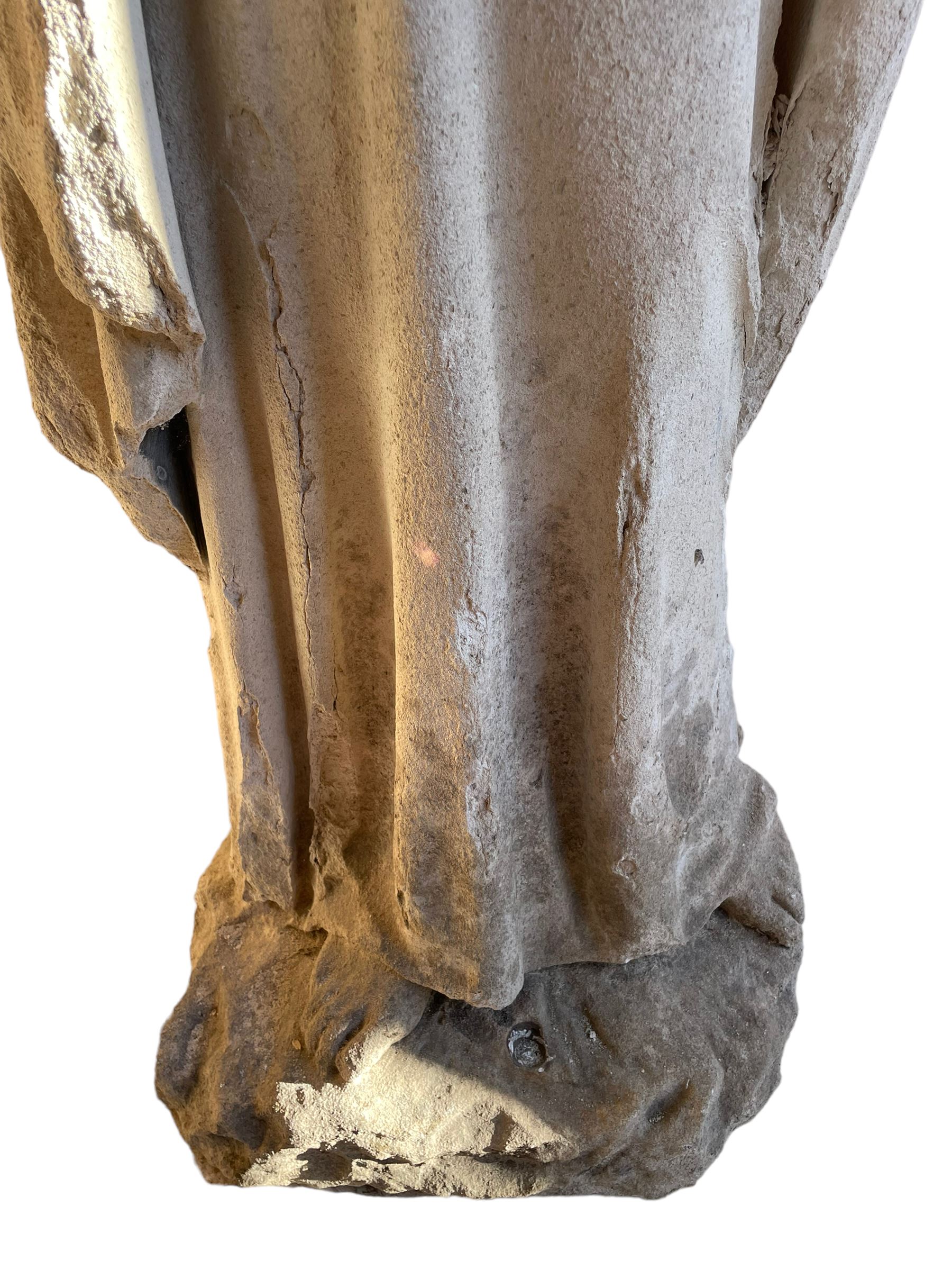 19th century weathered carved sandstone figure of Jesus Christ depicted as the Good Shepherd, draped in robes and holding a lamb, on a naturalistic base