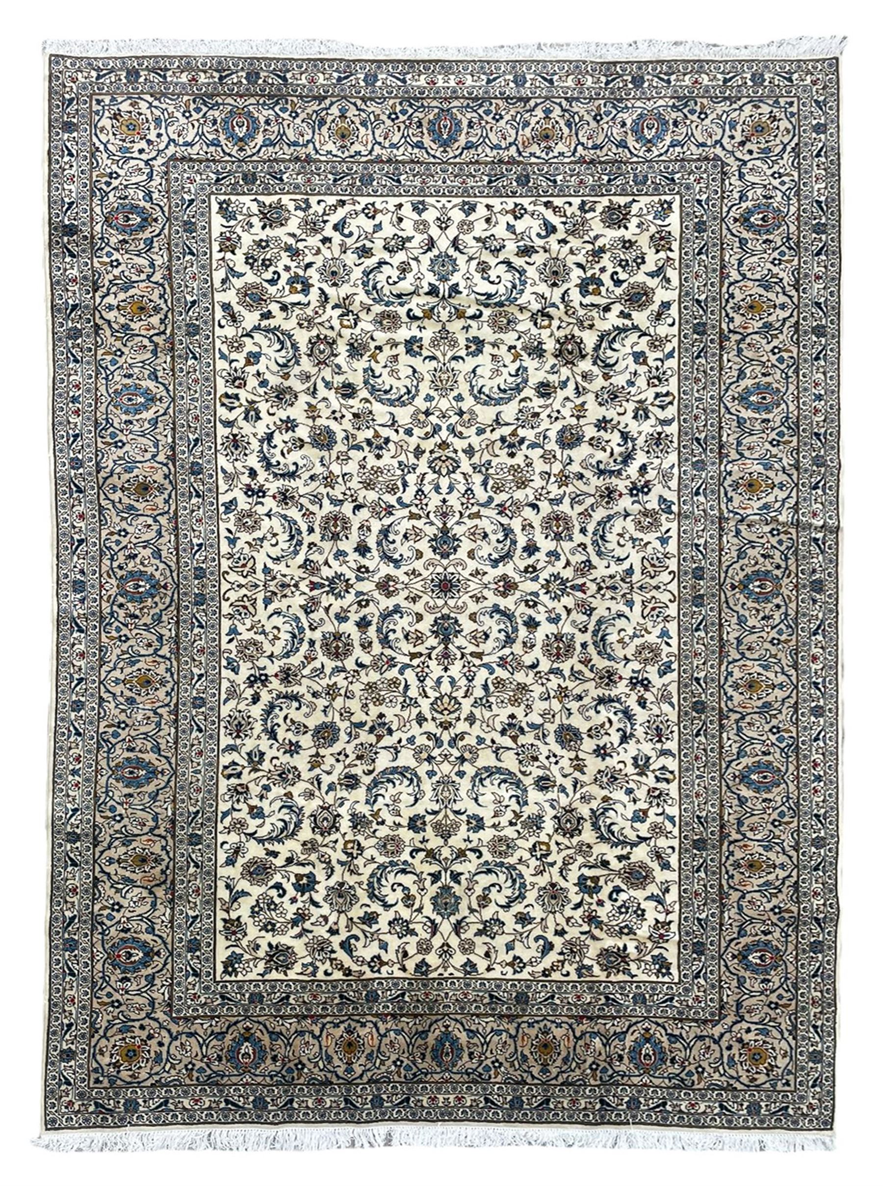 Persian Kashan ivory ground rug, overall floral design, the field decorated with scrolling foliage and palmettes, scrolling border within guard stripes decorated with small floral motifs