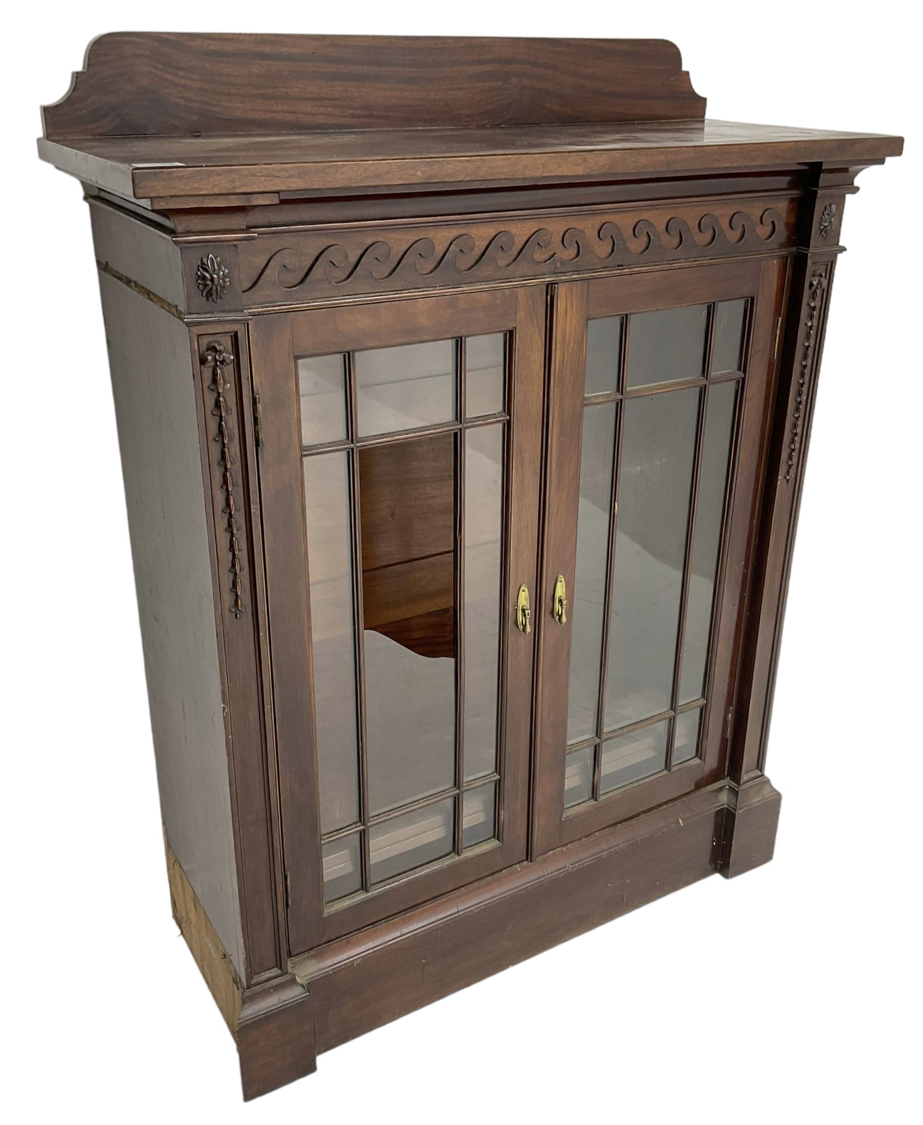 19th century mahogany display cabinet, rectangular top over frieze decorated with Vitruvian scroll mount, enclosed by two astragal glazed doors, the upright rails decorated with trailing bellflowers, on moulded plinth