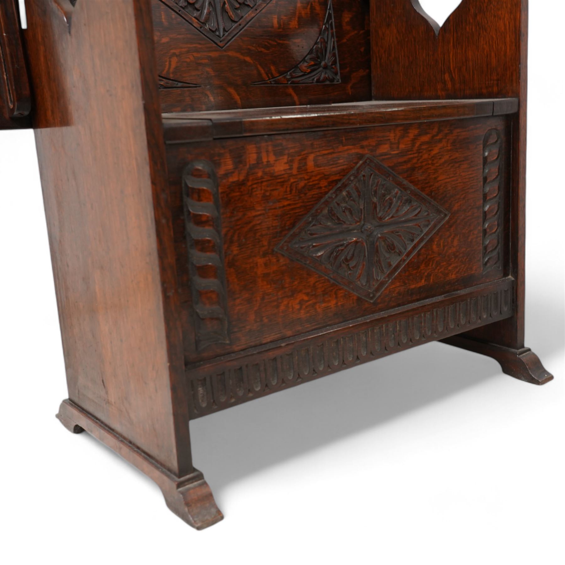 Early-to-mid-20th century carved oak monk's bench, metamorphic top with foliate lozenge carvings, over box seat with hinged lid, arcade carved lower rail on shaped feet