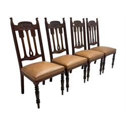 Set of four Edwardian walnut dining chairs, foliate carved high back over sprung seat upholstered in tan faux leather, raised on turned supports