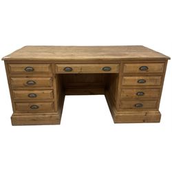 20th century waxed pine kneehole desk, rectangular top over nine drawers with cup handles, on moulded plinth base