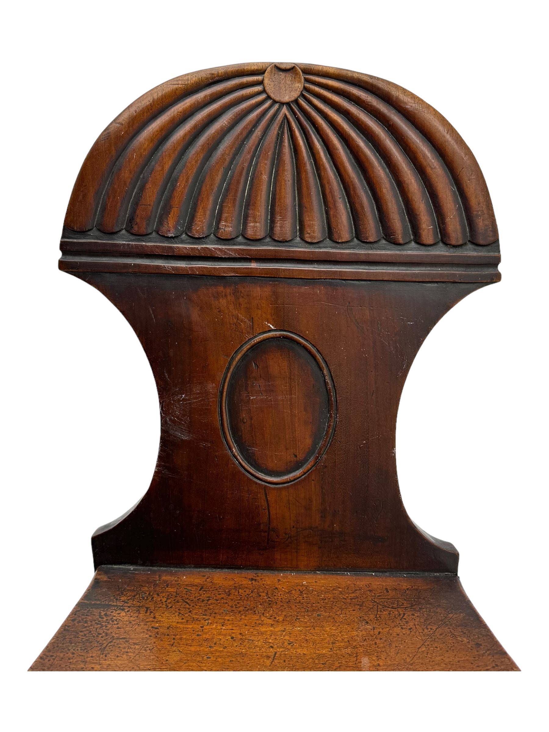 Regency mahogany hall chair, the carved back with shell motif and oval medallion, supported by turned front legs and splayed rear legs